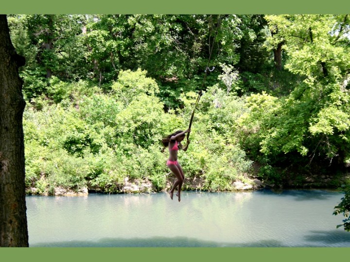 A woman in a pink bikini using a rope swing to drop into a deeper area of water at Pillsbury crossing.
