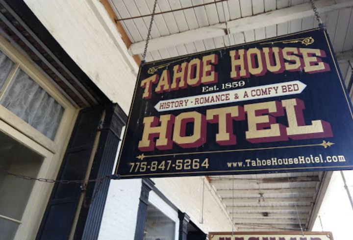 A Tahoe House Hotel historic sign hangs above a wooden boardwalk in downtown Virginia City, NV