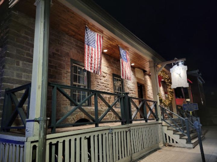 Brick exterior of the Old '76 House House restaurant and tavern in Tappan, New York with American flags hanging from the front porch