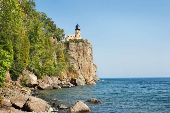 Subject: Horizontal, early fall view of the Minnesota Lake Superior shoreline, with the Split Rock Lighthouse on a rocky cliff in the distance.Location: Split Rock Lighthouse State Park, Minnesota