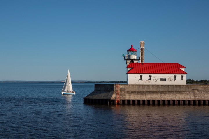 A breakwater lighthouse on Lake Superior with a sailboat.