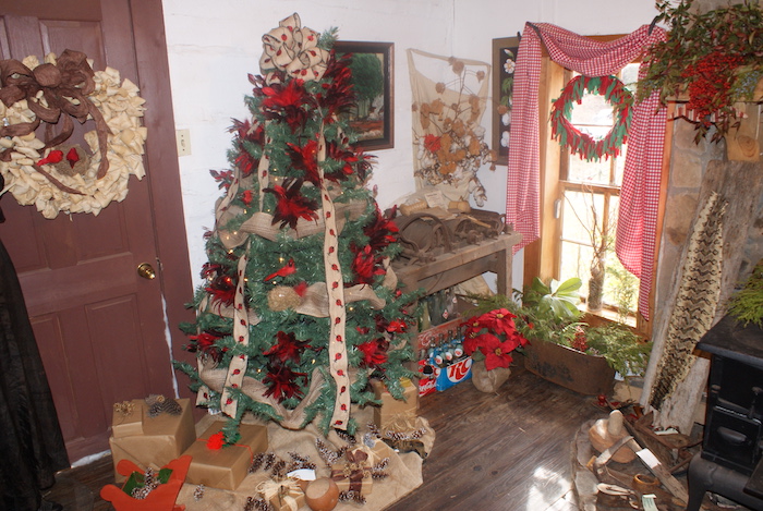 Interior of a cabin showing a decorated tree and many other decorations and antiques at LaGrange Historic Site's Christmas in the Country event, which allows guests to experience a pioneer Christmas in Alabama.