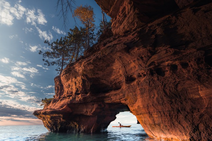A lone kayaker exits a sea cave on The Apostle Island National Lakeshore in Wisconsin in Fall.