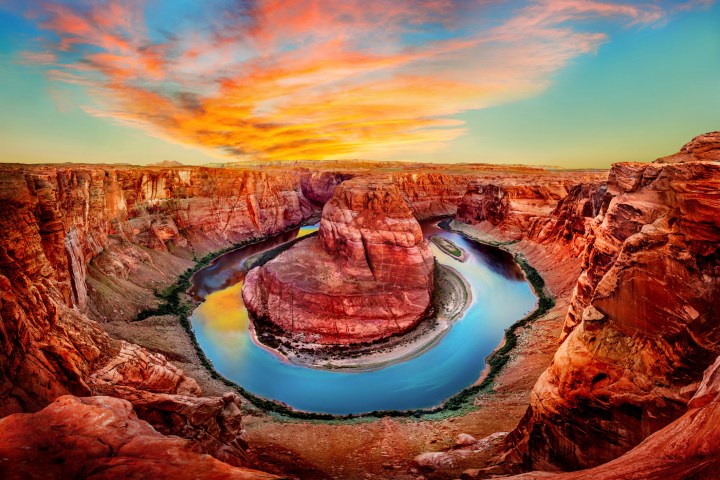 The Colorado River stretches around the glowing red rocks of Horseshoe Bend in Page, AZ at dawn