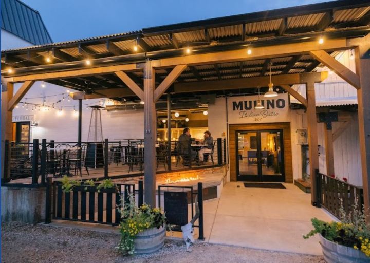 Exterior of Mulino Italian Bistro in Lander, Wyoming depicting outdoor patio seating at dusk with string lights