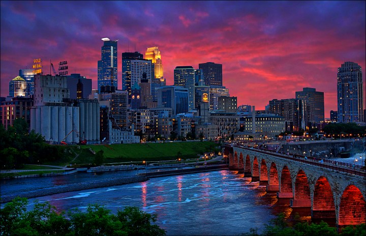 Minneapolis, Minnesota - view of the Stone Arch pedestrian bridge crossing the Mississippi River leading into Minneaolis's West Bank riverfront area that includes Mill Ruins Park and the Upper St. Anthony Falls Lock and Dam.